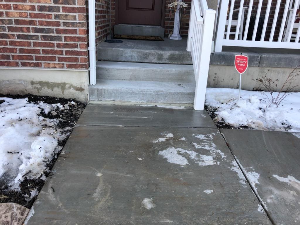 Concrete sidewalk repair at residential entrance with steps and snow, Landmark Lifting.