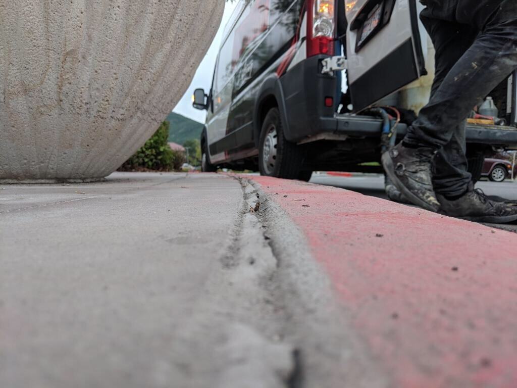 Concrete sidewalk repair with a worker and service vehicle on site.